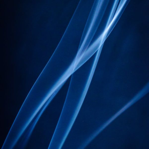 Abstract flowing lines of light in cyan color on a dark background.