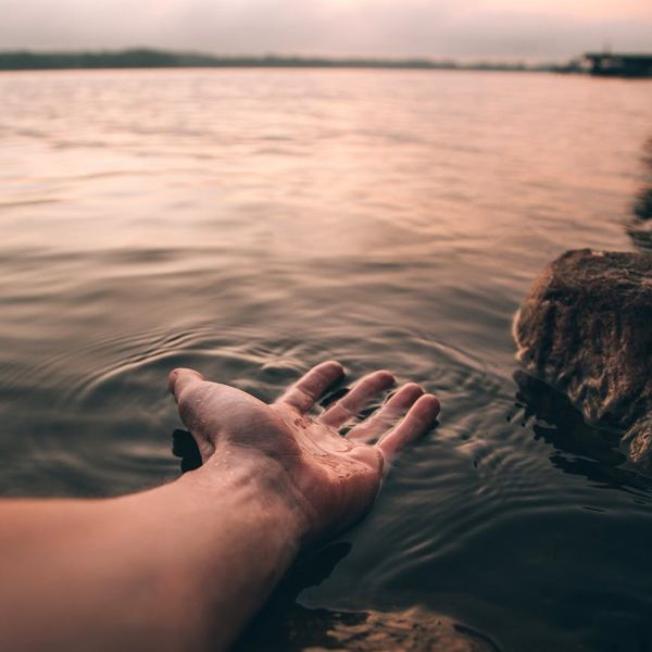 Person feeling energized and stretching arms upwards against a sunrise.